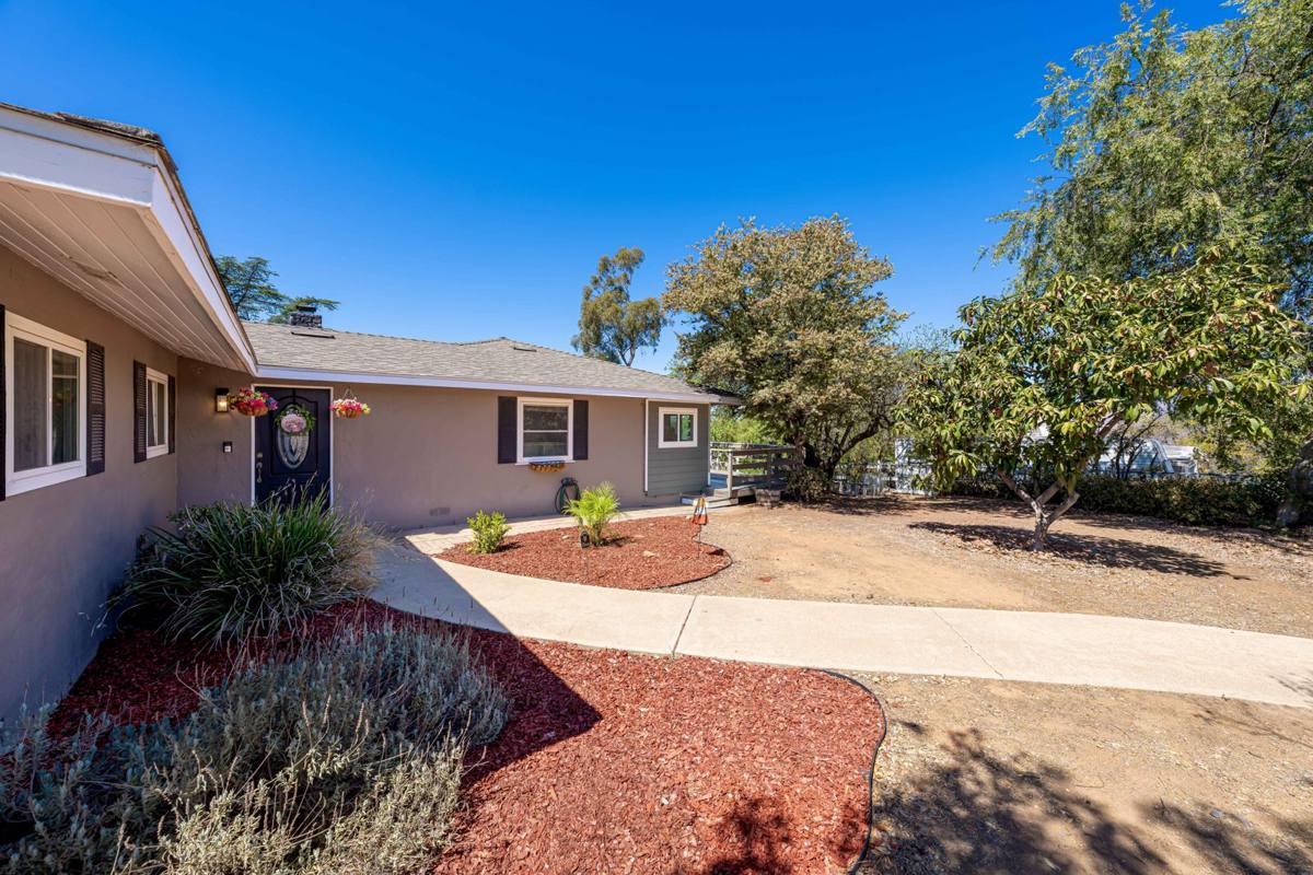 Front entry with landscaped beds, curved walkway, and mature shade trees
