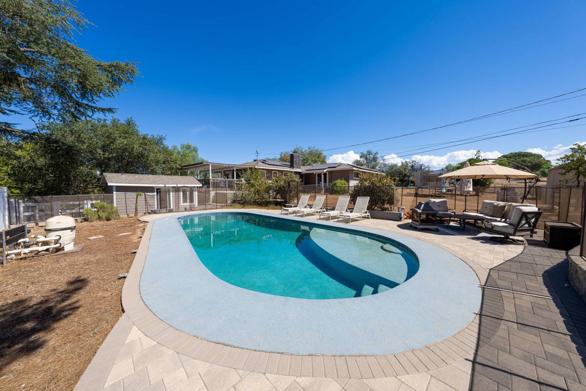 Pool with lounge area, pool house, and the home behind
