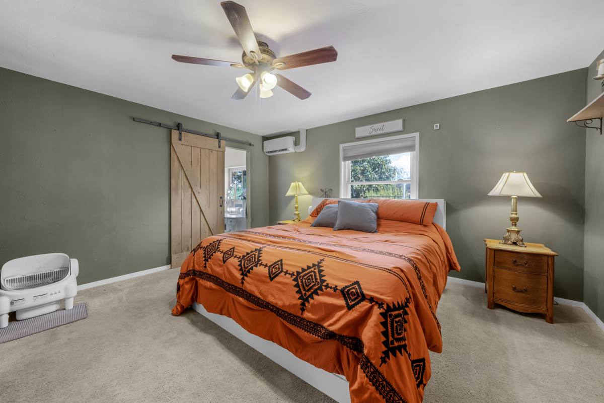 Primary bedroom with sliding barn door and ceiling fan